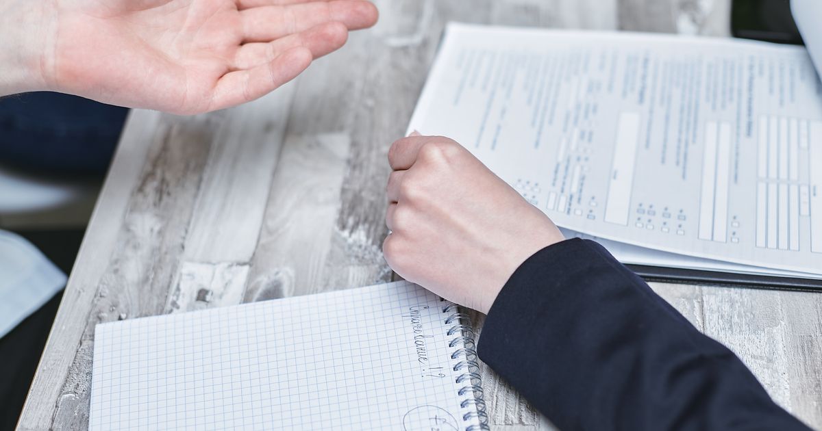 木目の机の上で、書類とノートを前に2人が話し合っている手元