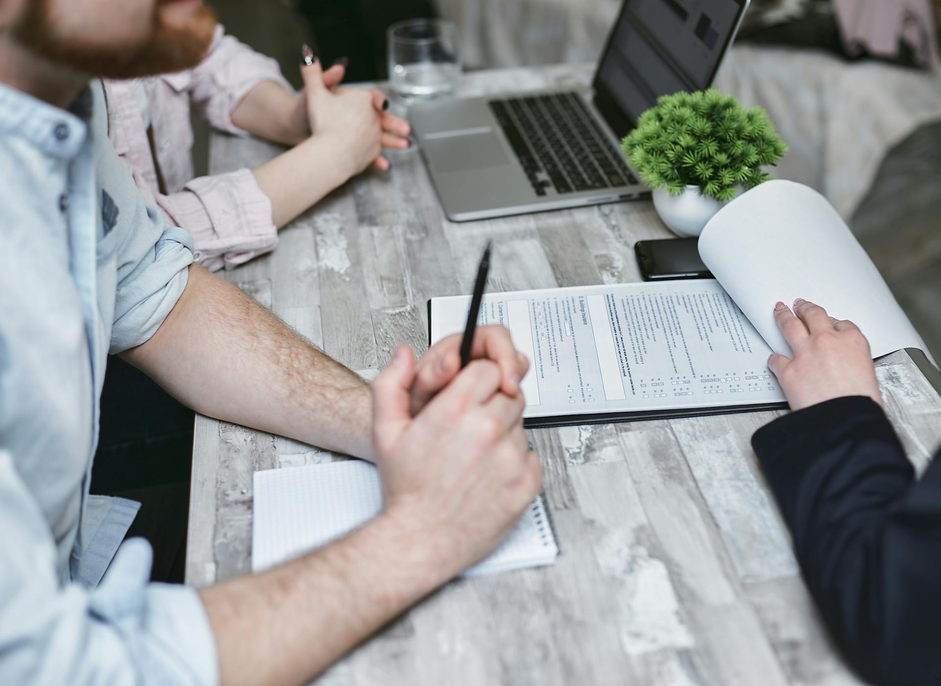 Close-up of a business meeting with documents and laptop on a white table.