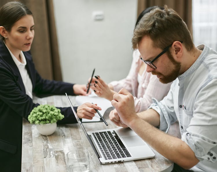 A Bearded Man Looking At The Laptop On The Table