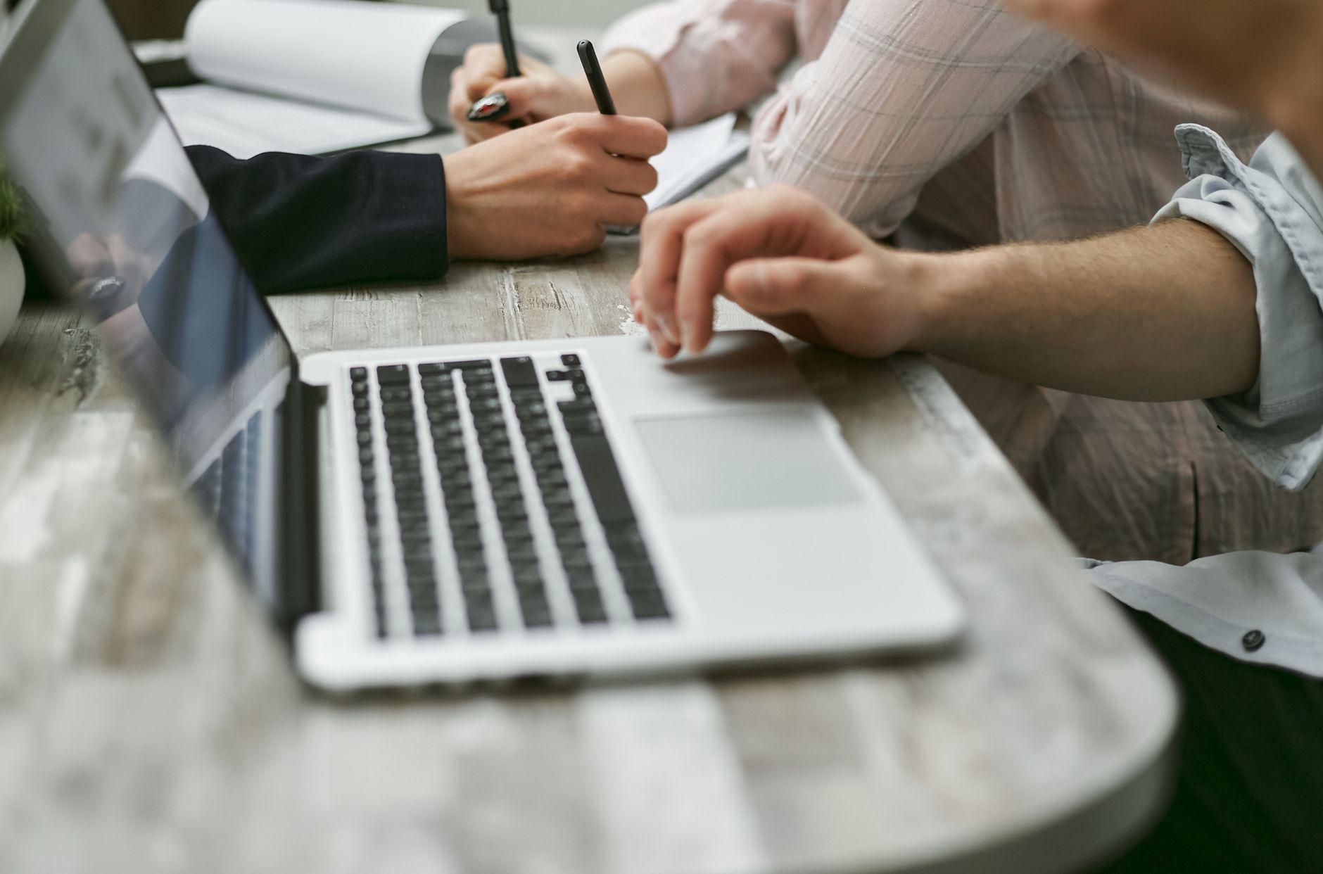 People reviewing notes and documents next to a laptop.