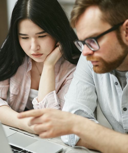 Free Two professionals collaborating on a laptop, focusing on work with intense concentration. Stock Photo