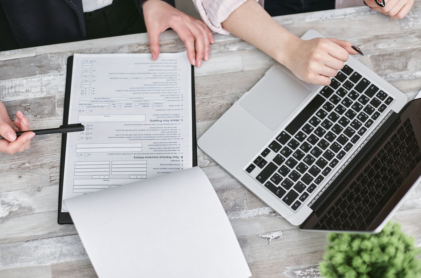 Two people reviewing documents beside a laptop