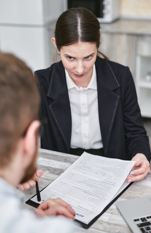 Free A Woman Holding a Document Talking to a Man Across the Desk Stock Photo