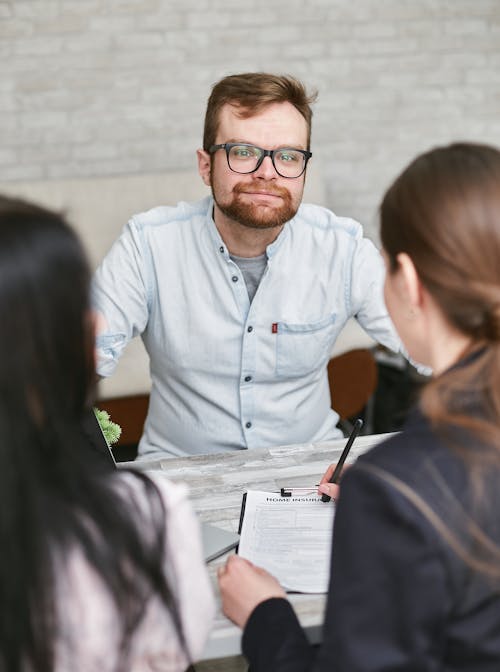 Bearded Man Sitting at Table Wearing Black Framed Eyeglasses