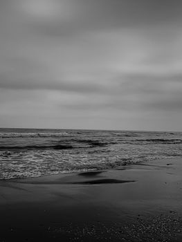 Grayscale view of waves crashing on Ramsar beach, portraying a serene coastal scene.