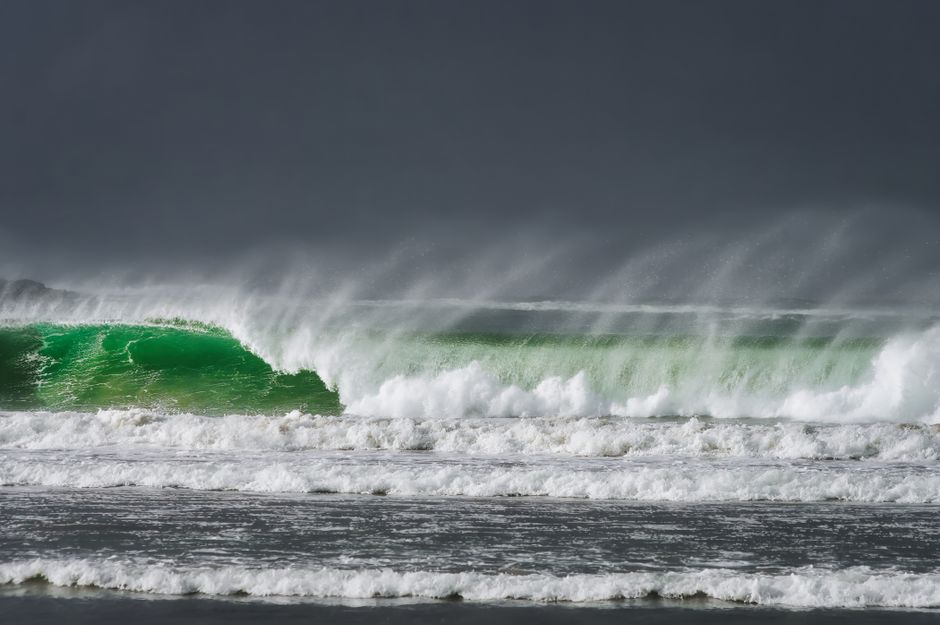 Powerful waves crashing on a beach in Ireland under a dark sky, capturing the ocean's dynamic energy.