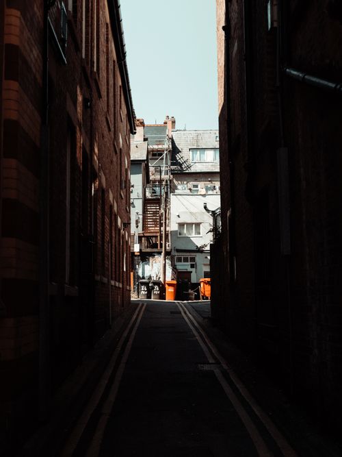 Free A narrow urban alleyway with brick walls, showcasing architecture and shadows. Stock Photo