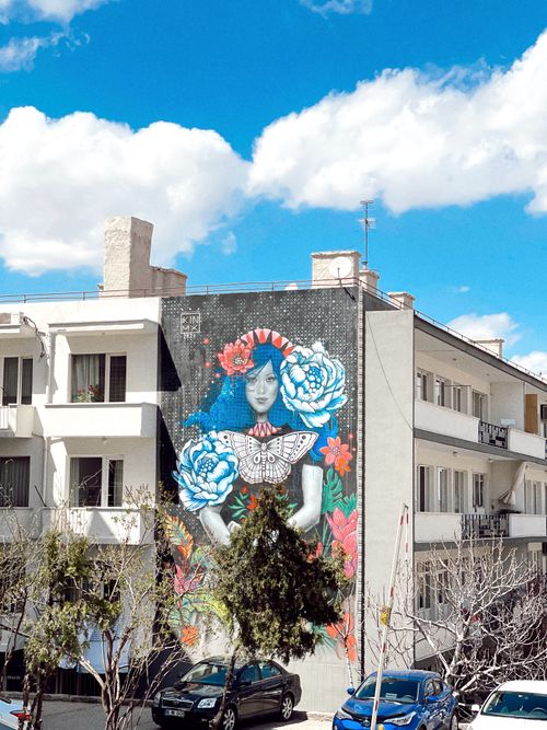 Free Vibrant street art mural on a city apartment building wall, featuring a woman's portrait. Stock Photo
