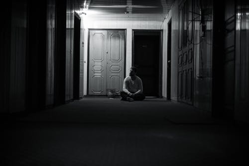 A Grayscale of a Man Sitting on the Floor