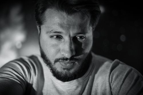 Free Grayscale portrait of a bearded man deep in thought with a soft focus background. Stock Photo