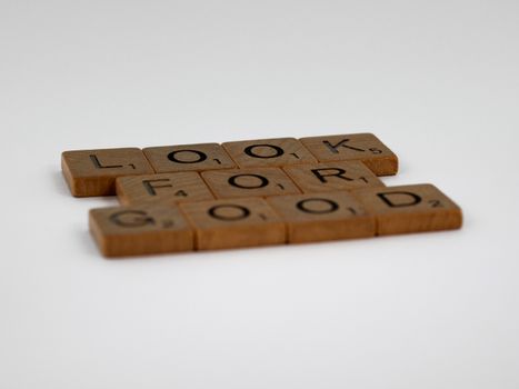 Wooden tiles spelling 'LOOK FOR GOOD' laid out in a minimalist style on a plain background.