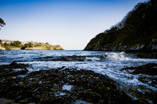 Free A beautiful ocean view with waves crashing against the shore under a blue sky. Stock Photo
