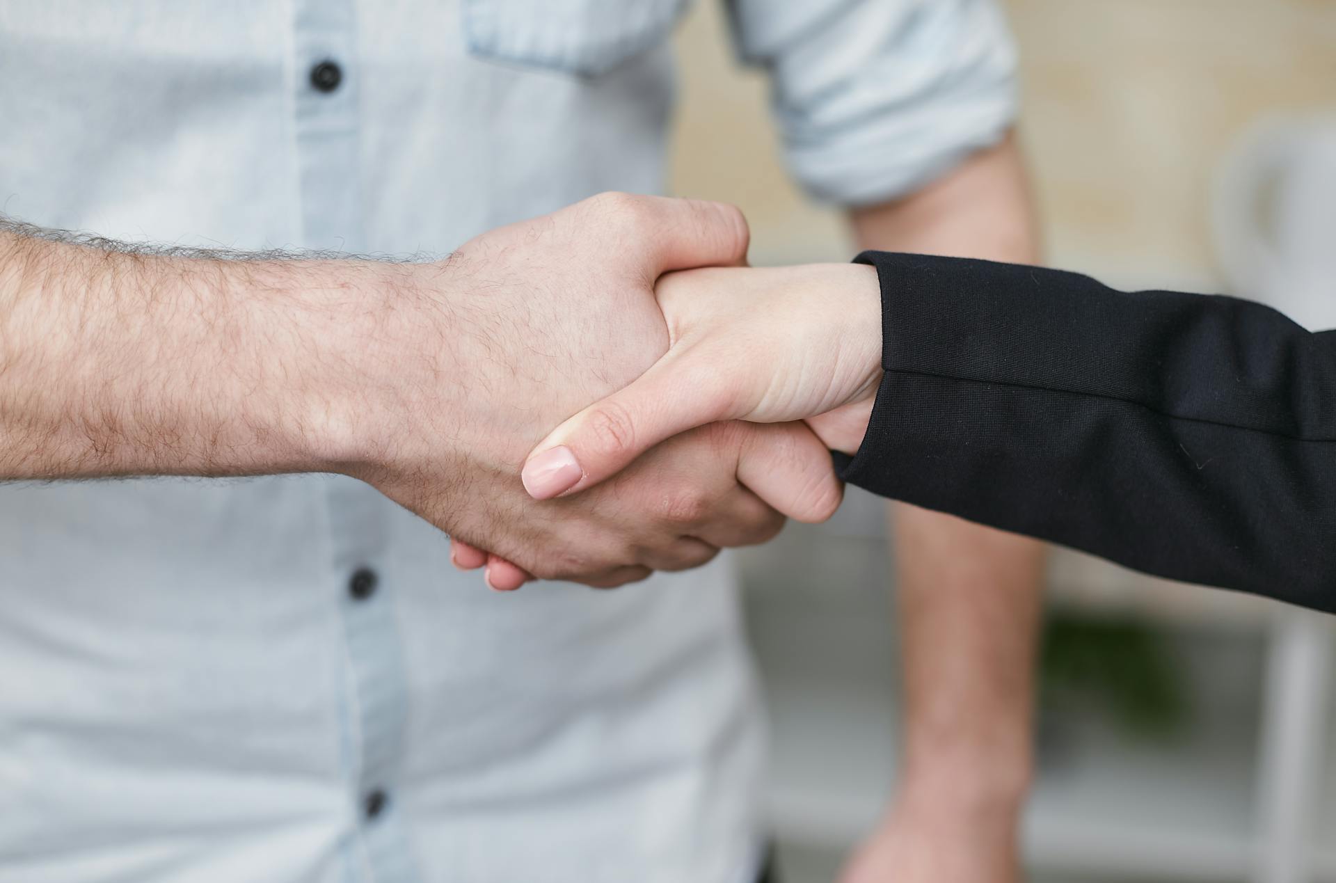 Close-up of two individuals shaking hands symbolizing business agreement and partnership.