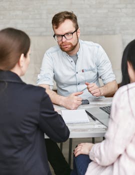 Group of adults engaged in a focused work meeting indoors, discussing plans.
