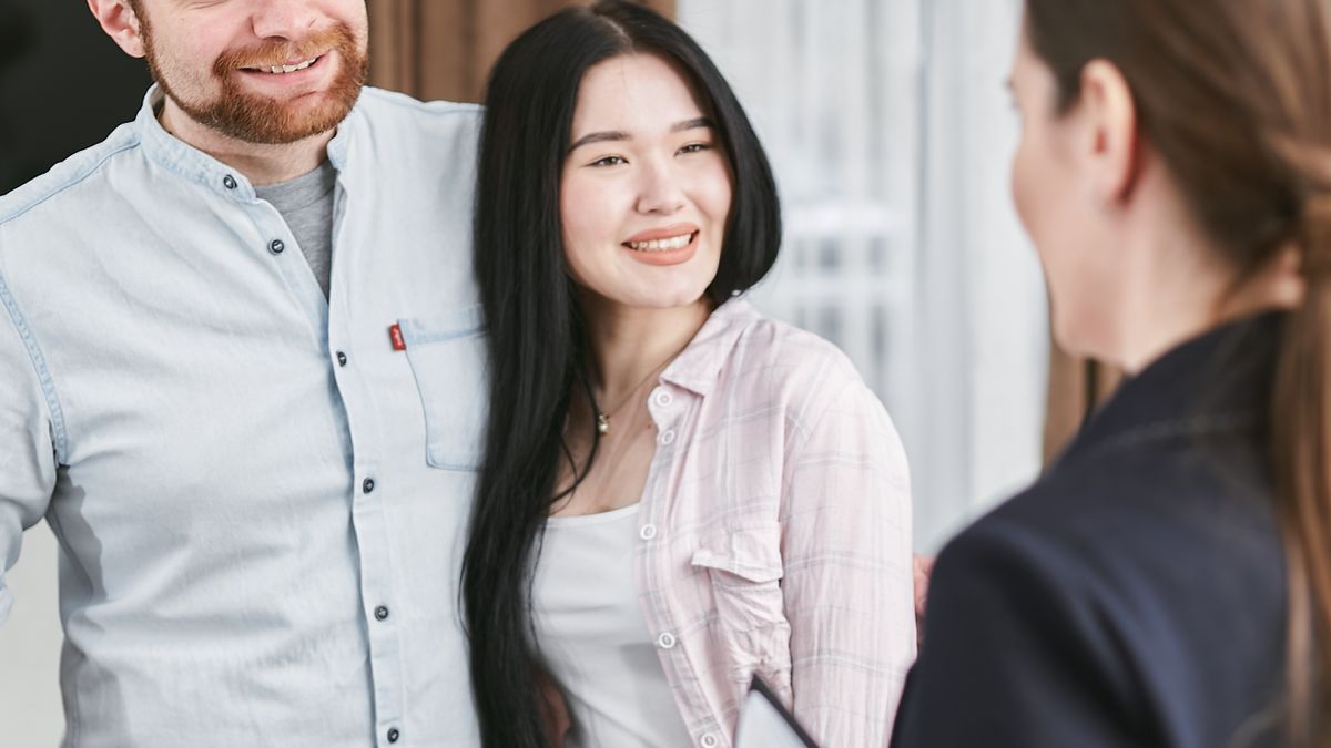 Agent immobilier souriant en discussion avec un couple de clients