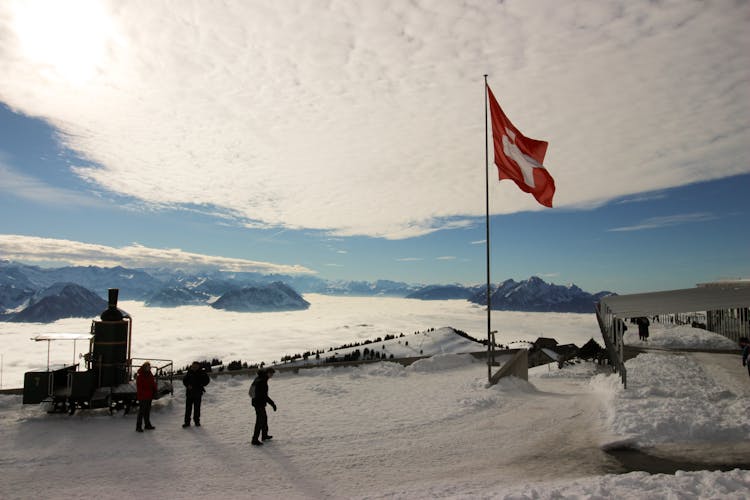 High-saturated Silhouette Photography Of Three Person Standing Near Red And White Cross Printed Flag