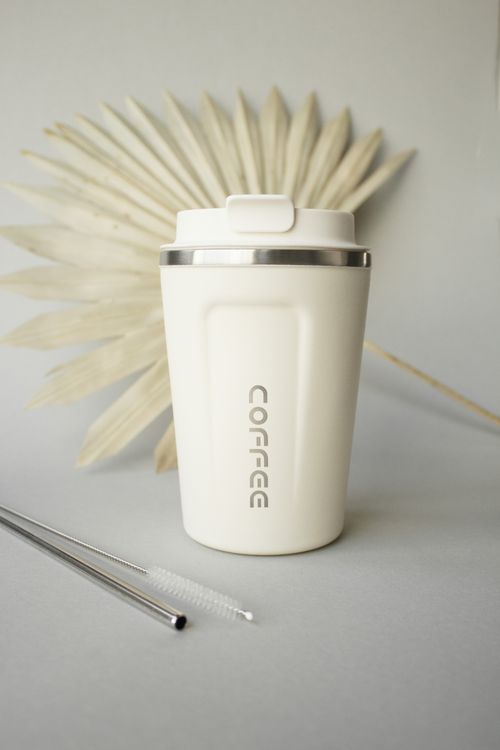 Free Elegant beige coffee tumbler with metal straws and palm leaf, perfect for modern coffee enthusiasts. Stock Photo