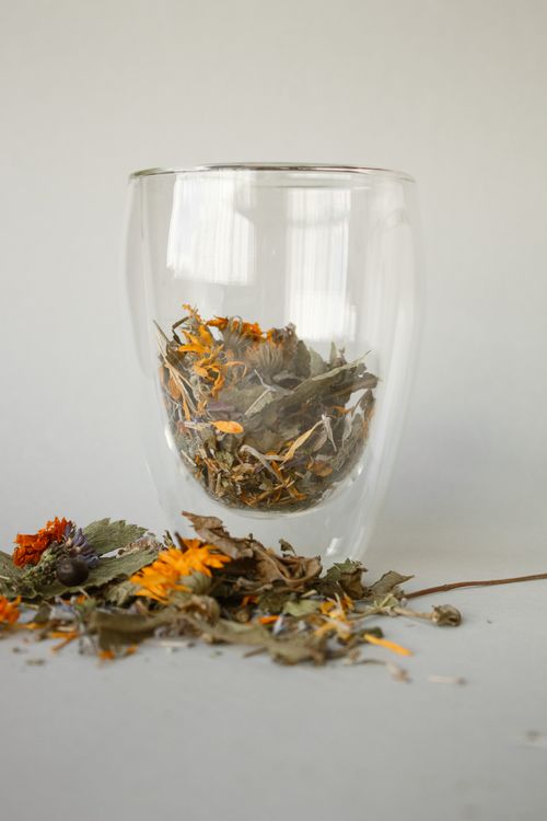 Free Glass filled with aromatic dried leaves for herbal tea on a studio background. Stock Photo