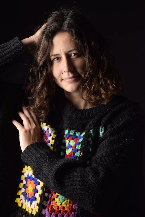 Photo of a Woman in a Black Knitted Sweater Looking at the Camera