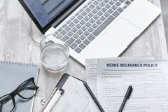 Top view of a desk with laptop, insurance forms, and office supplies, ideal for business or finance topics.
