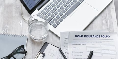 Top view of a desk with laptop, insurance forms, and office supplies, ideal for business or finance topics.