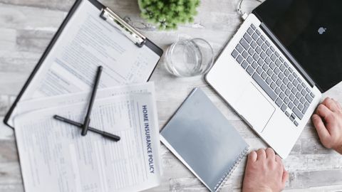 Top view of home insurance forms, laptop, and documents on a desk, conveying a professional office setting.