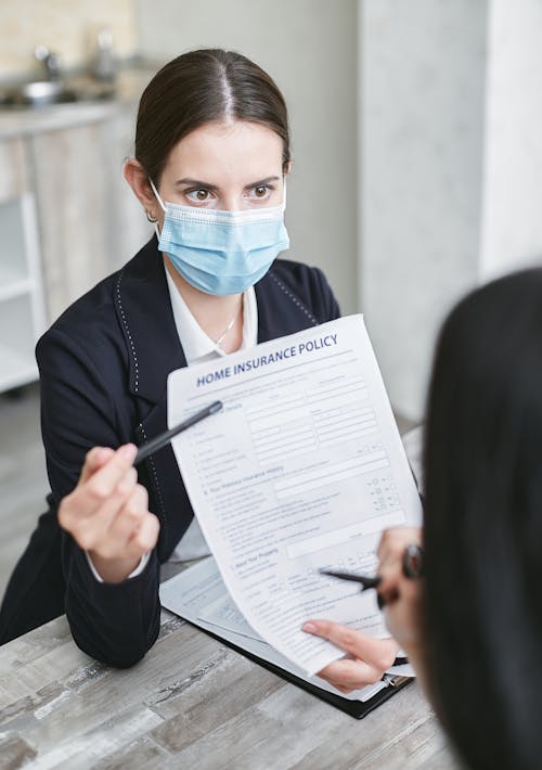 Free A Woman Wearing Face Mask Holding a Home Insurance Policy Stock Photo