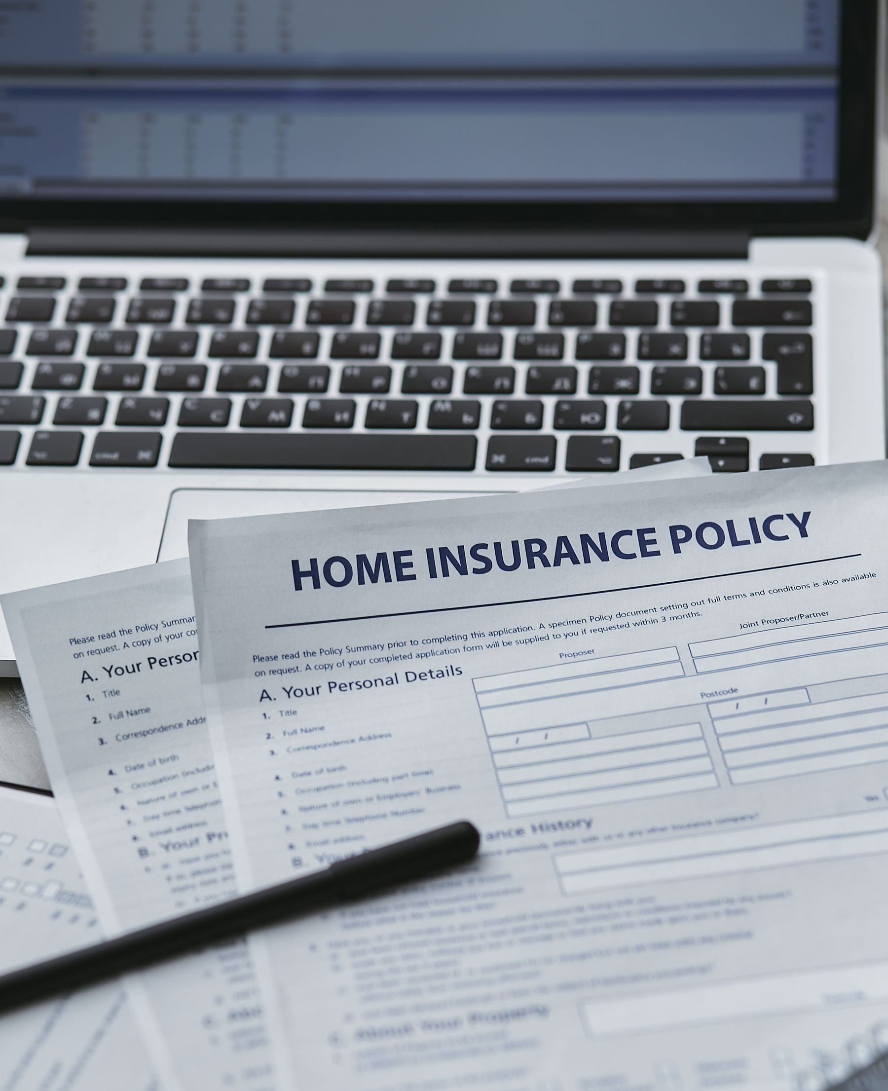 Insurance paperwork and laptop on a desk