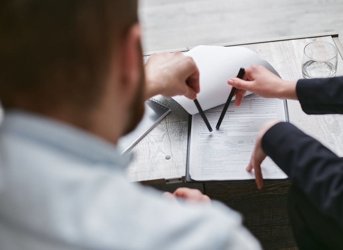 Two people analyzing a business contract with pens on a table
