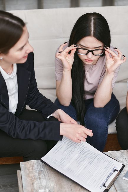 Focused businesswomen discuss contract details while reviewing important documents in an office setting.