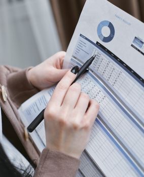 Hands holding a pen review a family budget document with graphs and tables.