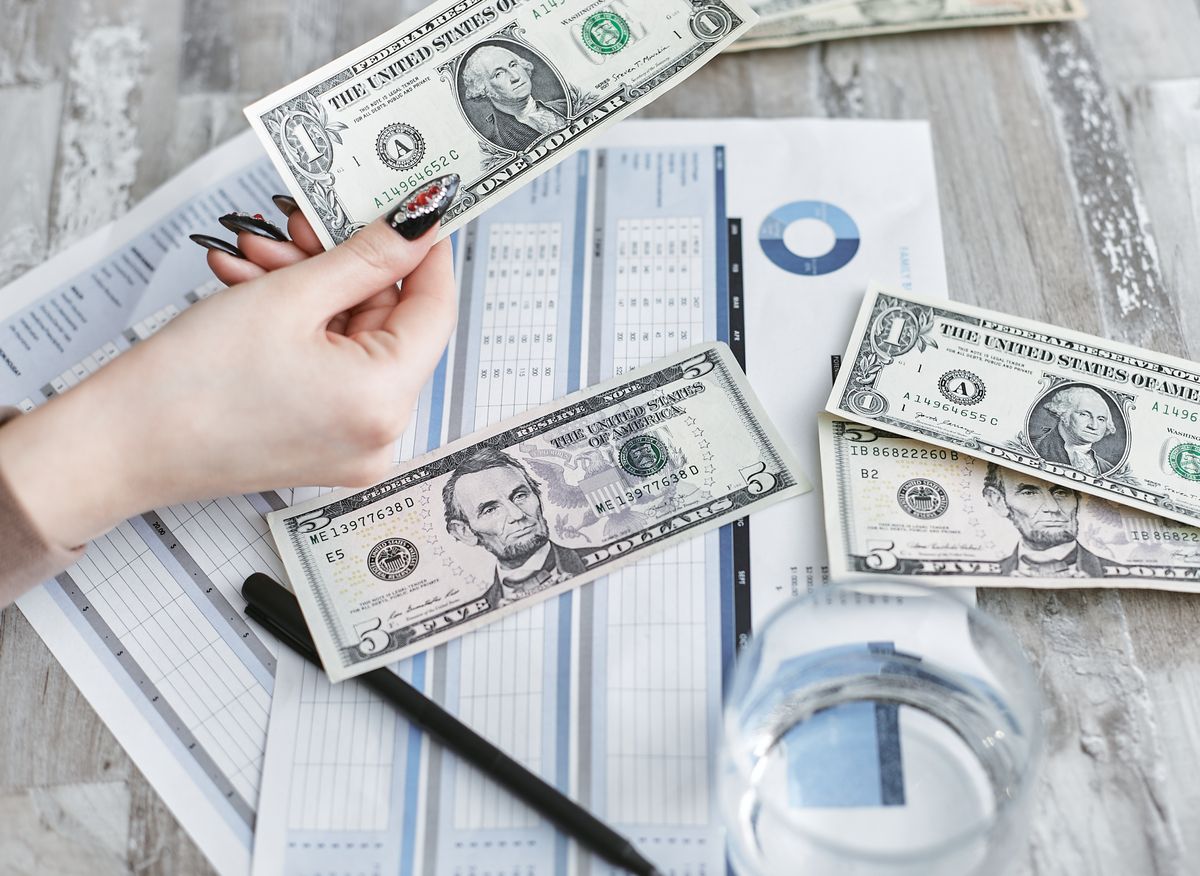 Hands reviewing cash beside financial charts