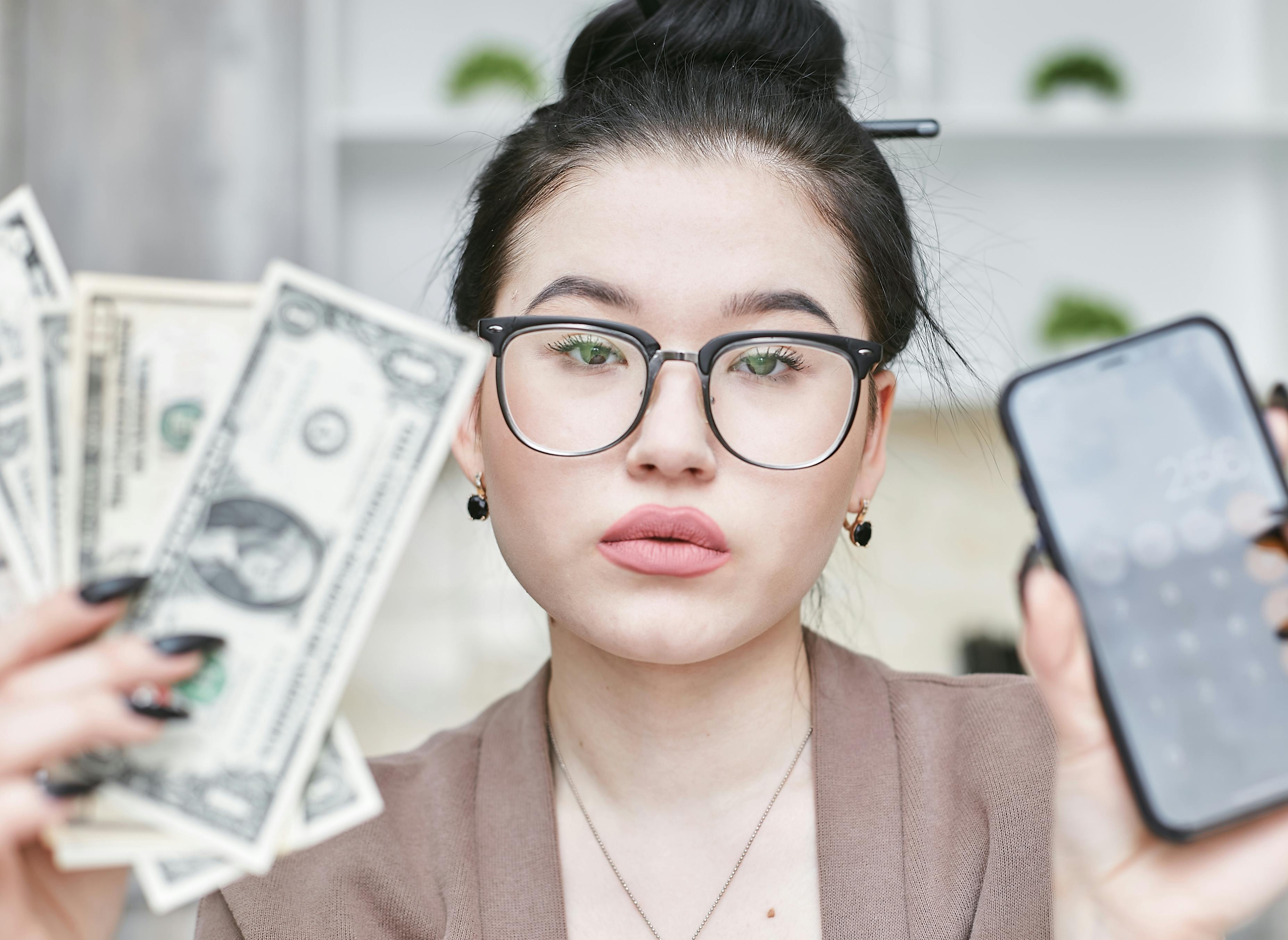 a woman holding an iphone and cash money