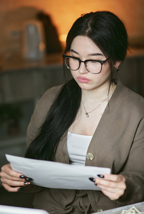 A Woman wearing Eyeglasses holding Paper 