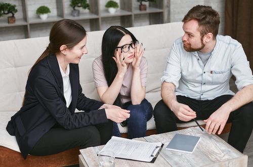 Free Three adults discussing documents and plans during a collaborative business meeting indoors. Stock Photo