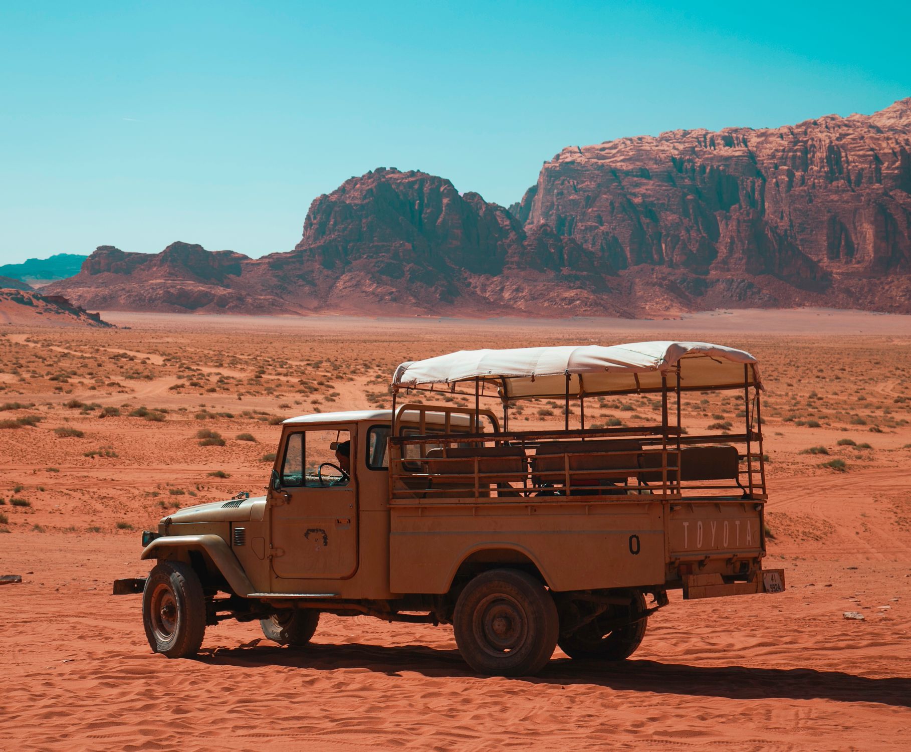 A lone vintage vehicle sits in the vast Wadi Rum desert in Jordan, offering an adventurous ambiance.