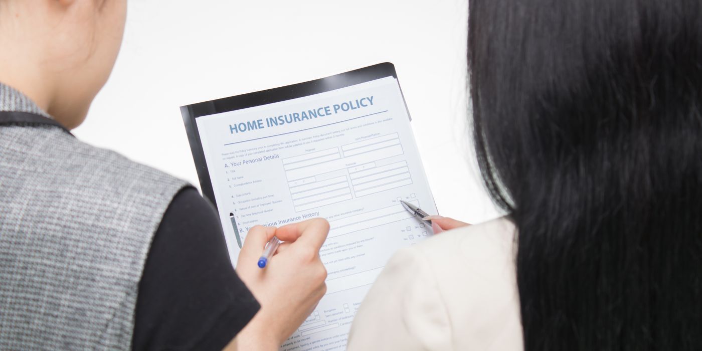 Two women examining home insurance policy form, focused on details.