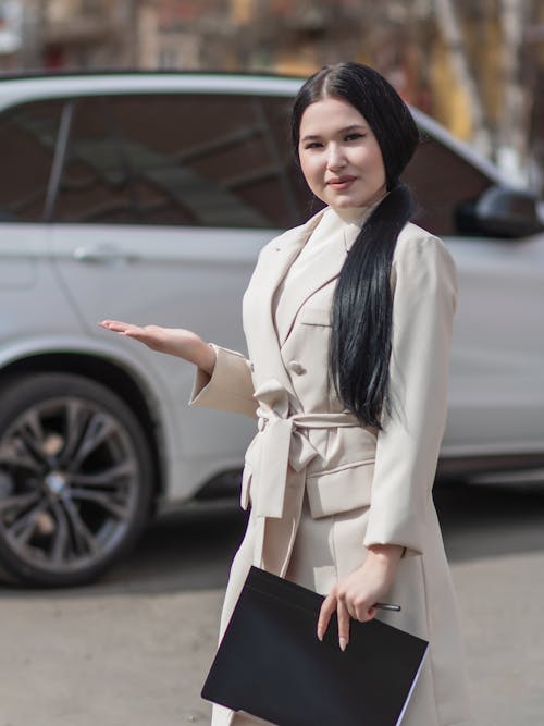 Free Woman in White Coat Standing Near the White Car Stock Photo