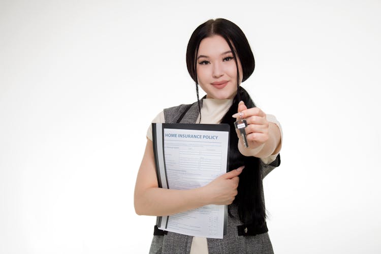 A Woman Holding Key And Insurance Policy