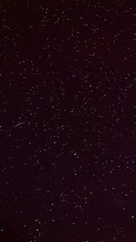 A mesmerizing view of a starry night sky with a visible shooting star streaking across the universe.