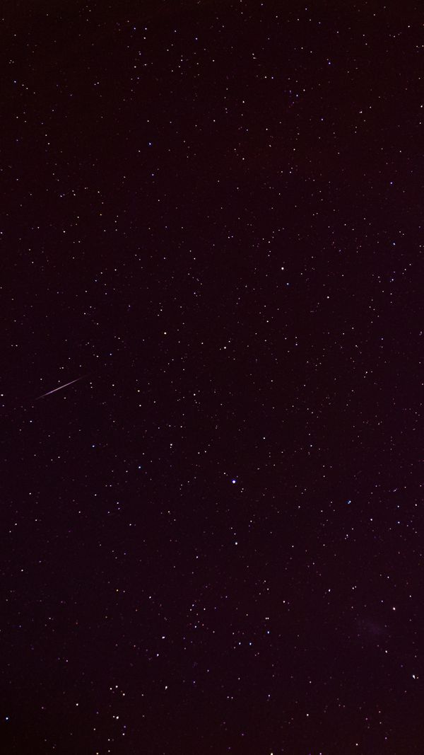 Uma vista hipnotizante de um céu noturno estrelado com uma estrela cadente visível riscando o universo.