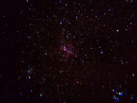 A mesmerizing view of a star-filled sky featuring a distinct pink nebula in deep space.