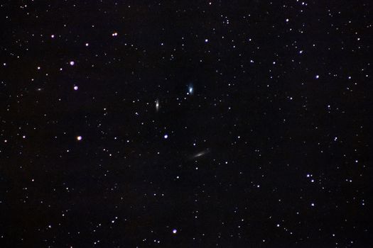 A beautiful wide-angle shot of a clear starry night sky, featuring distant galaxies shimmering brightly.