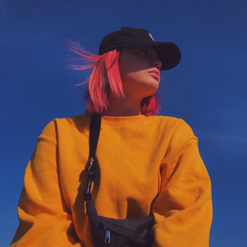 Woman With Colored Hair Wearing Yellow Long Sleeve Shirt And Black Cap