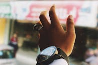 一只戴着手表和戒指的手，伸向模糊的风景特写