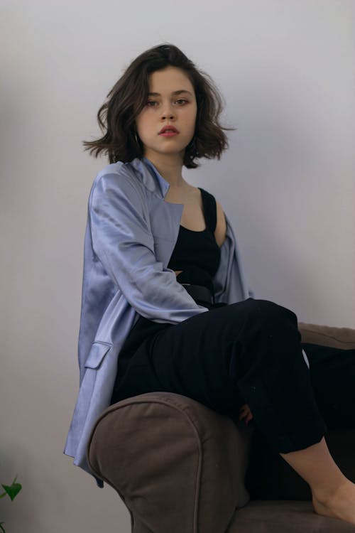 Free Young Woman In Black and Blue Outerwear Sitting On An Armchair Stock Photo