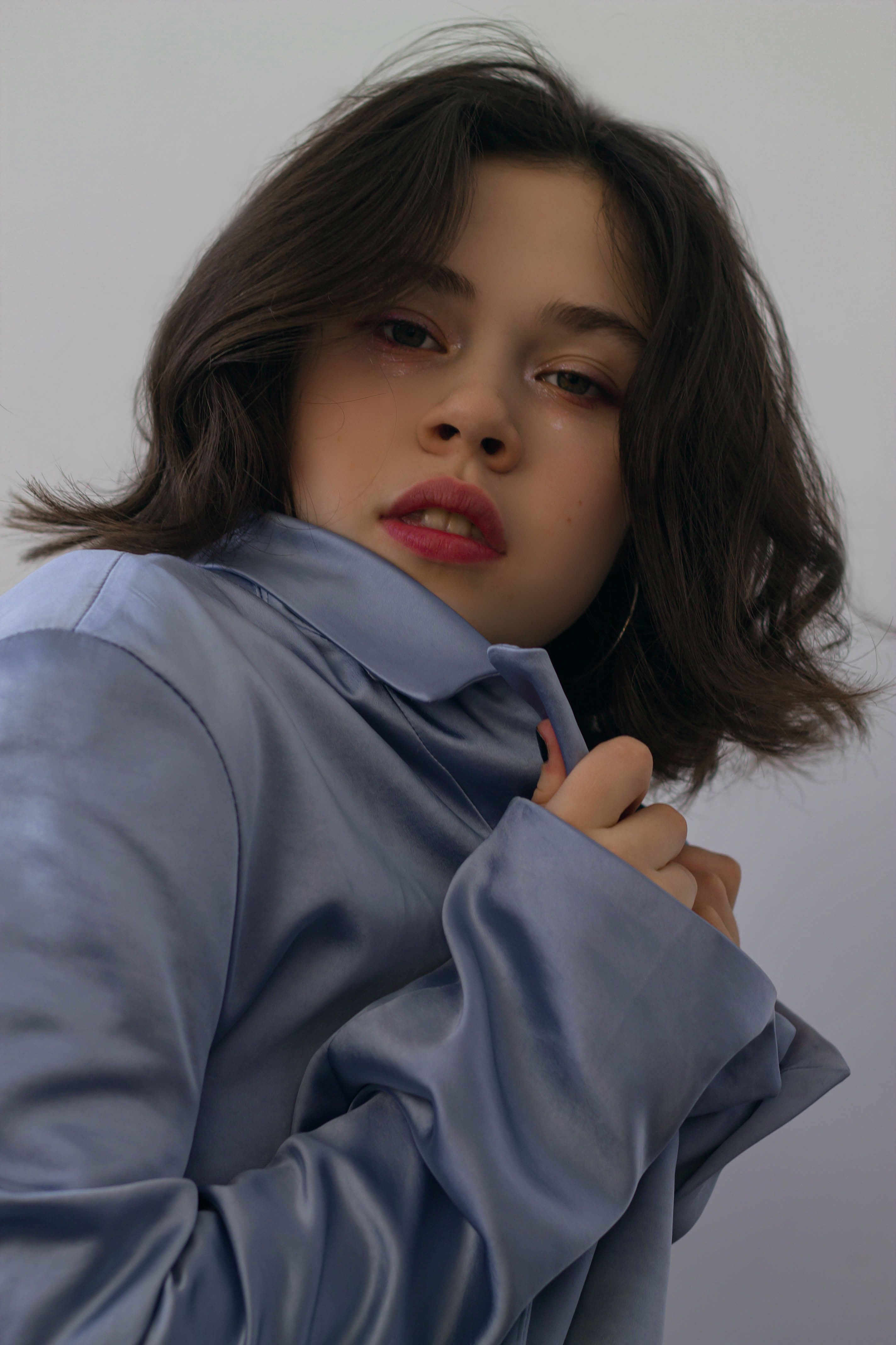 Elegant portrait of a woman in a satin blazer, striking a poised pose with a serene background.