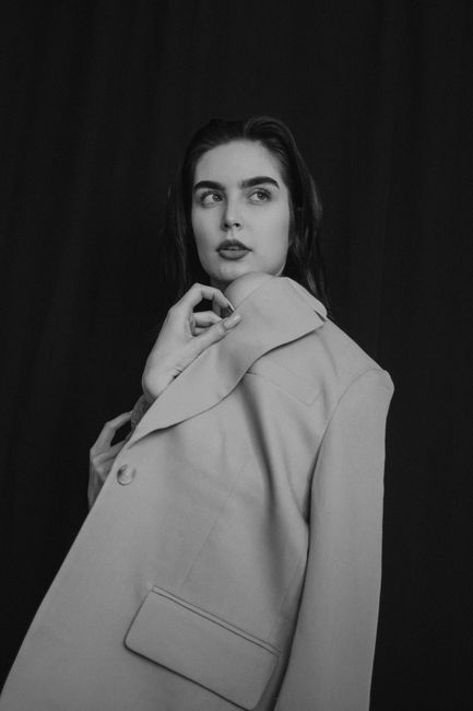Striking black and white portrait of a woman wearing a coat, exuding elegance.