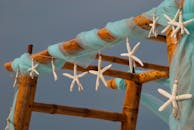 这座优雅的海滩婚礼拱门装饰着海星和蓝色织物，非常适合热带海滨仪式