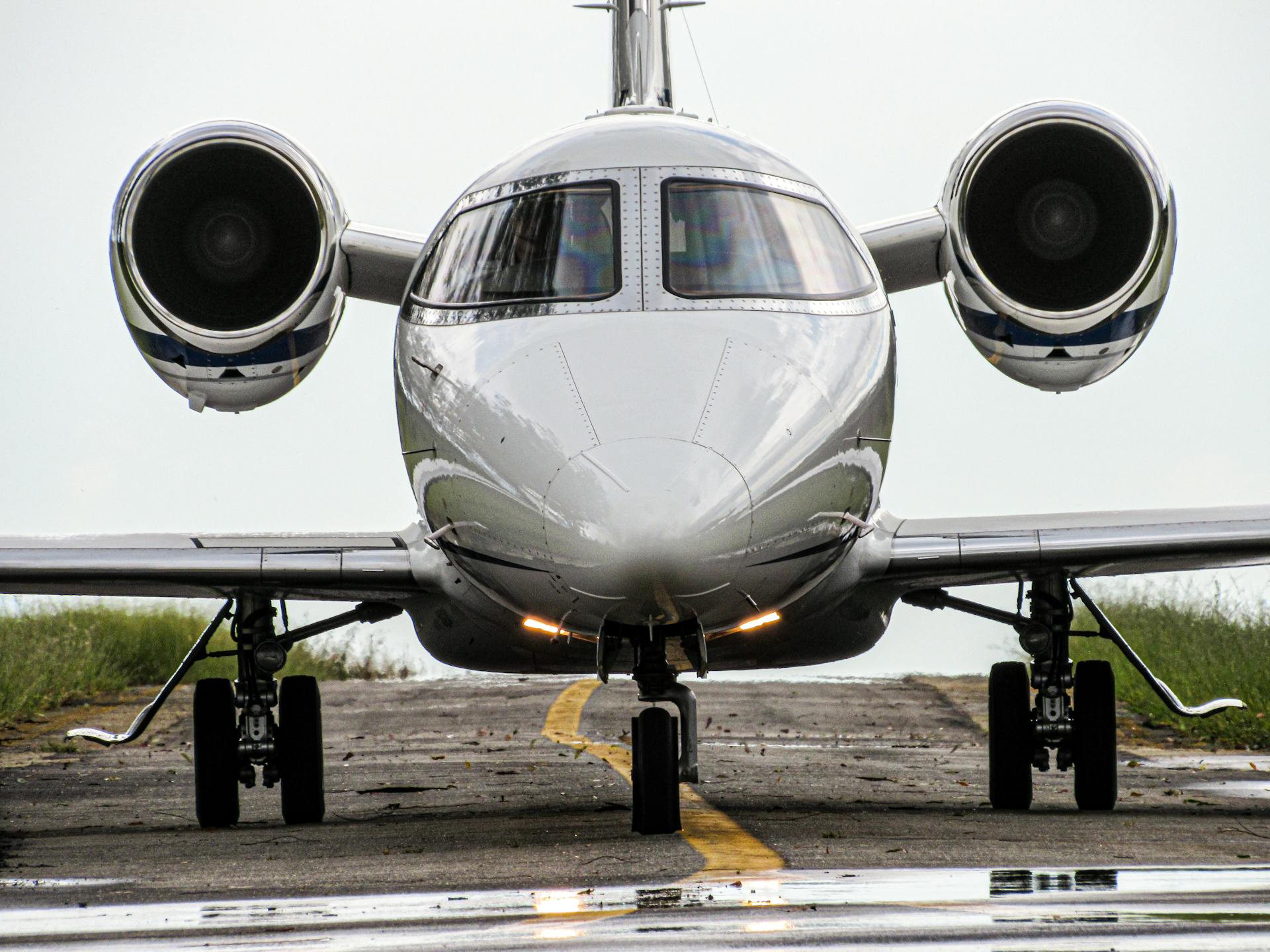 Front view of a sleek jet aircraft on a runway, ready for takeoff in daylight.